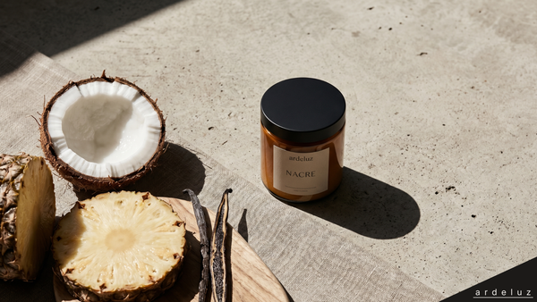 ardeluz NACRE candle in amber glass jar with coconut, pineapple, and vanilla beans on raw concrete surface