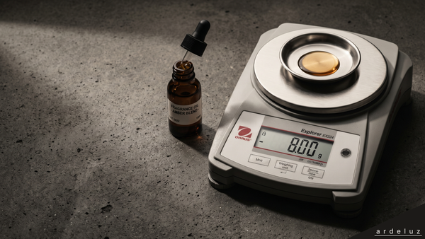 Soy wax candle pour with fragrance oil being measured by weight on a digital scale, dark concrete surface